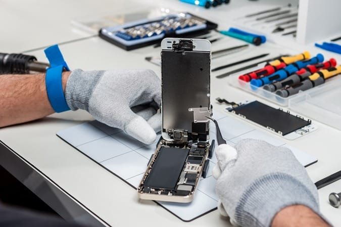 iTech Norwich technician diagnosing and cleaning a water-damaged phone motherboard
